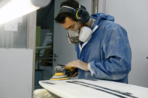 Appletree crew member Joao sanding kiteboard in factory Appletree Surfboards